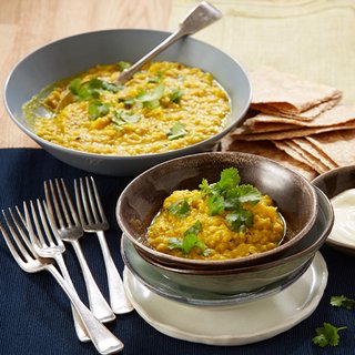 2 bowls of yellow dhal, 1 small side dish and 1 main dish, topped with coriander and served with chappati and yoghurt