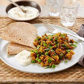 Minced turkey keema, dotted with peas and topped with coriander, on a plate with a chapati and a spoonful of yoghurt