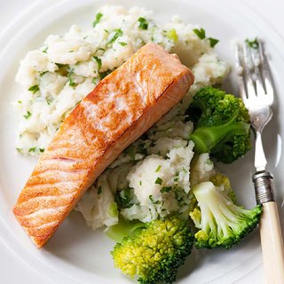 A piece of cooked salmon served with broccoli on a bed of spring onion mash