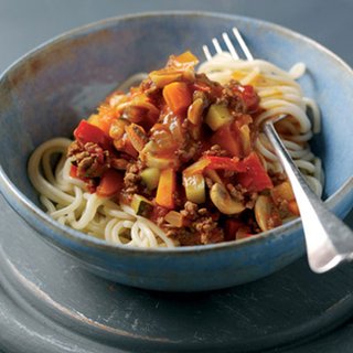 A serving of spaghetti bolognese, with mushrooms, carrots and red peppers