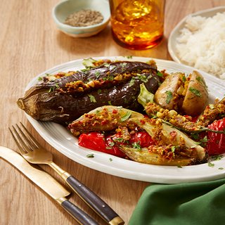 A plate of aubergines, large red peppers, onions and potatoes stuffed with a masala paste mix, served with rice.