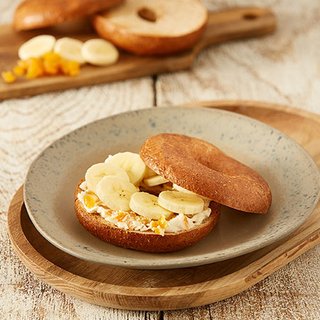Sliced banana on a bagel spread with soft cheese and dried apricots