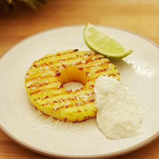 A grilled slice of pineapple, served with yoghurt and a slice of lime