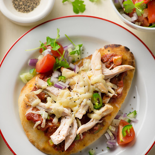 Naan bread topped with tomato, roast chicken slices and melted cheese