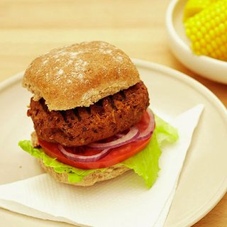 Chilli beef and bean burger served with salad in a bun, with a side of corn on the cob