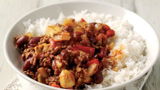 A bowl of chilli made with beef, mushrooms, kidney beans and peppers, served over rice