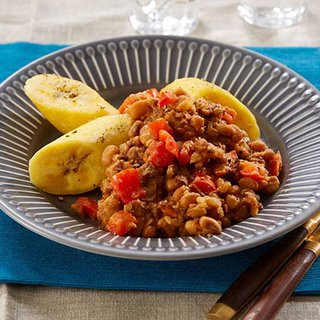 Honey bean, onion and red pepper stew, served in a bowl with 3 slices of steamed plantain.
