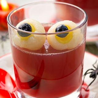 Two fruit eyeballs made from lychees and grapes, sat in a glass of jelly.