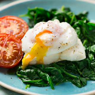 Poached egg on grilled haddock, with wilted spinach and tomatoes.