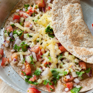 A fried folded wholemeal tortilla wrap filled with a mixture of chopped vegetables and melted cheese