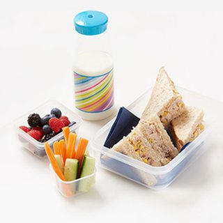 Tuna mayo and sweetcorn sandwich in a lunchbox, with carrot and cucumber sticks, mixed berries and small bottle of milk