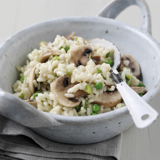 A bowl of cooked-rice risotto made with mushrooms and peas