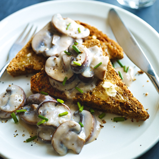 Sliced mushrooms in a white sauce, served on triangular slices of wholemeal toast