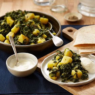 A bowl of curried spinach and potato chunks, served with chapati