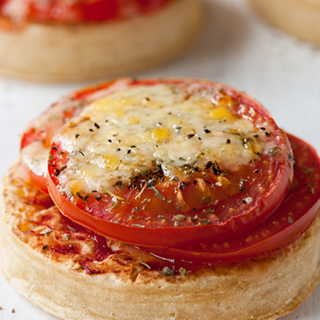 A pizza topped with tomato purée, tomato slices and melted cheese