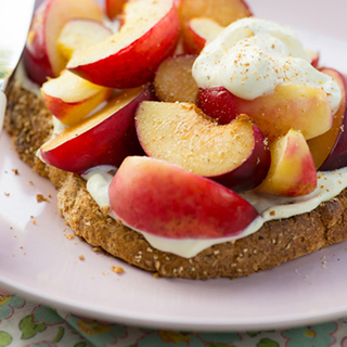 Sliced grilled peaches served on wholemeal toast with spoonful of yoghurt