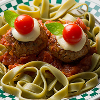 Two meatballs with tomatoes as eyes, on a bed of pasta