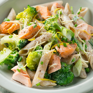 Pieces of salmon and broccoli served with pasta in a creamy sauce