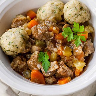A bowl with 3 dumplings, and a beef and vegetable stew