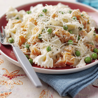A portion of pasta with sweet potato and peas, topped with grated cheese
