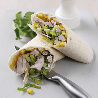 A wrap rolled and cut in half, filled with lettuce, chicken, cucumber and sweetcorn