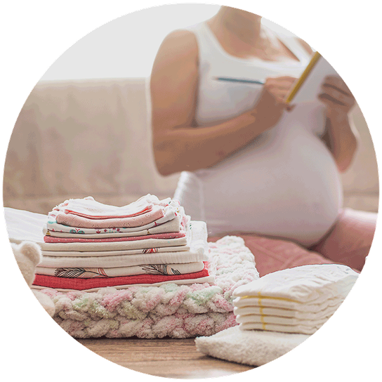Folded baby clothes are ready to be packed into a hospital bag, with a mum to be ticking off her checklist.