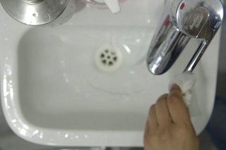 Turning off the tap using a disposable towel to avoid touching the tap with the hand