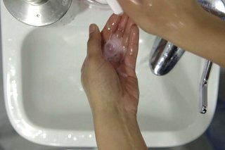 Hand applying soap from a soap dispenser over the sink