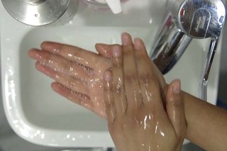 Rubbing hands together over the sink to cover hands with soap