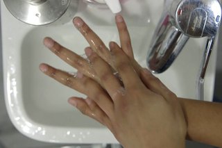 Rubbing the back of one hand with the other, cleaning between the fingers