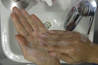 Fingers of the right hand cleaning the left palm over the sink