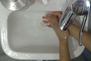 Rinsing both hands under the tap