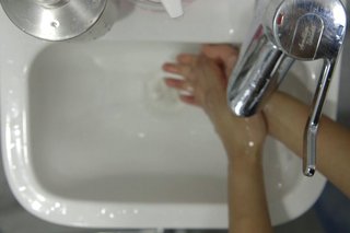 Rinsing both hands under the tap
