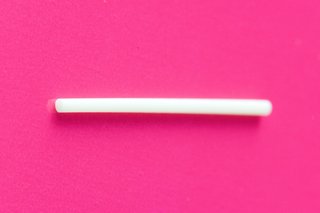 Contraceptive implant. It is white and made from plastic. It has the shape of a small stick.
