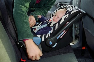 A baby being put into a car seat