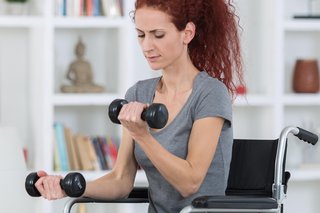 A person lifting hand weights while seated in a wheelchair