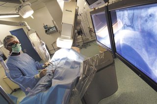 A heart specialist (cardiologist) performing a coronary angiography using an X-ray to guide them.