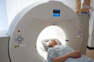 Person lying on their back with their head in a ring-shaped CT scanner.