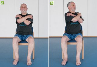 A seated man crossing his arms and then twisting his upper body to his left
