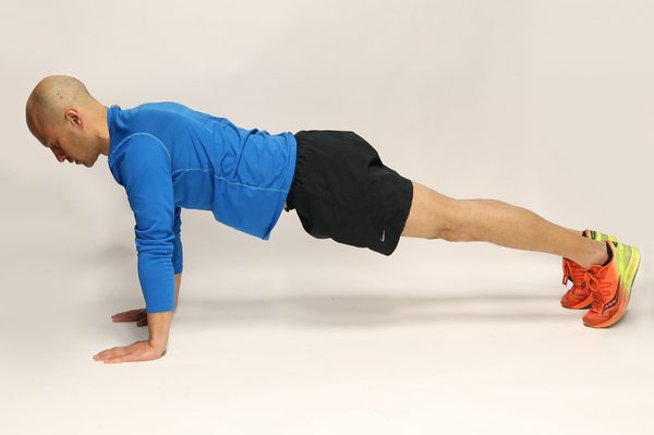 Man lying face down, propped up on hands and toes, with legs and arms straight.