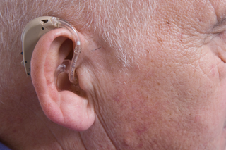 A hearing aid attached behind the ear. A plastic tube connects the device behind the ear to a mould inside the ear.