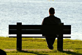 A man sitting on a bench looking out to sea