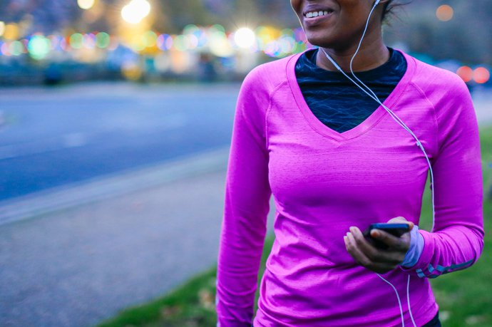 Seorang wanita mengenakan pakaian olahraga dengan headphone di dalamnya