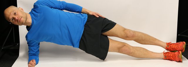 Man lying on side propped up on an elbow, with legs and hips raised in straight line from head to toe.