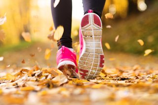 Close-up of a runner's pink running shoes, in autumn leaves on the ground